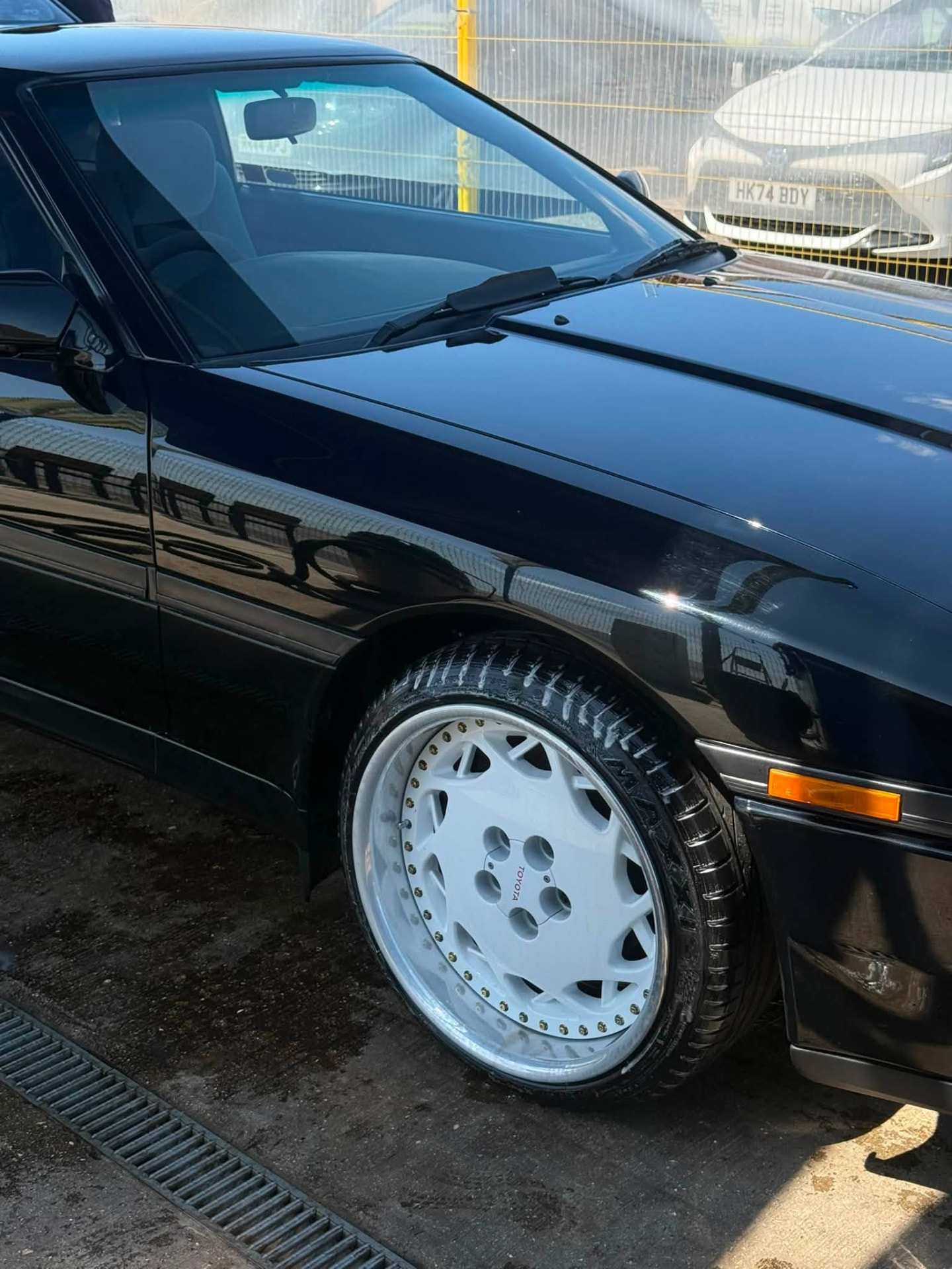 Modified black Toyota with white split-rim wheels detailed on site